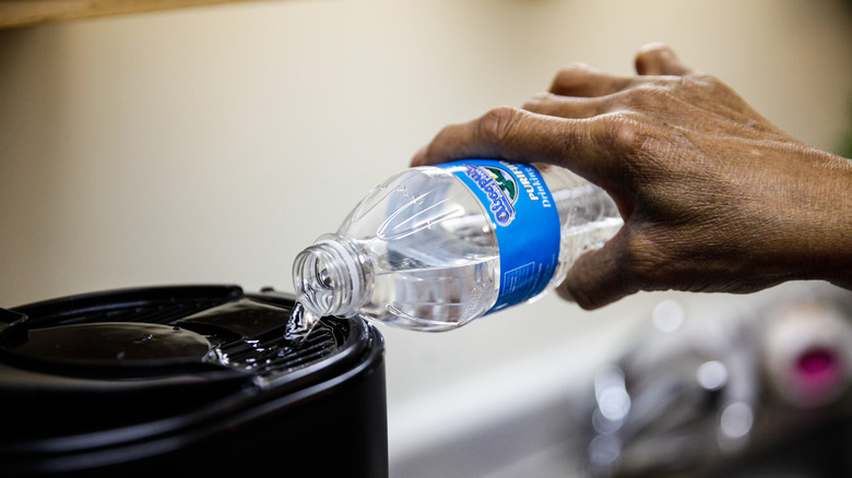 Pouring bottled water into coffeemaker