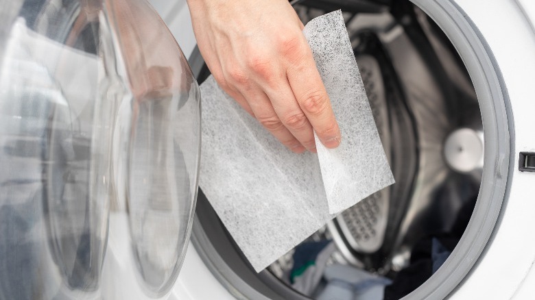 Hand putting dryer sheet in dryer