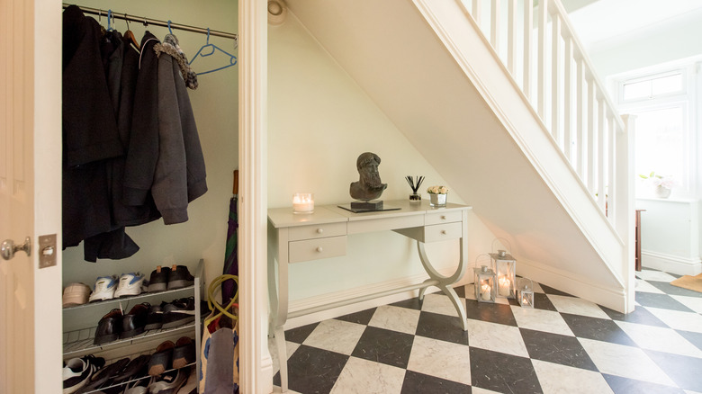 A foyer with a checkered floor, coat closet, and decorated table