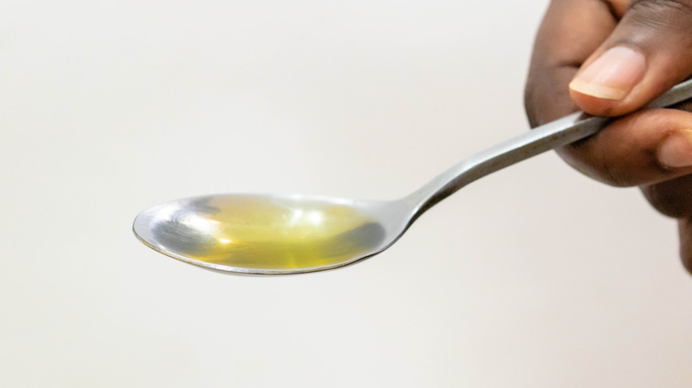 Hand holding spoon of oil