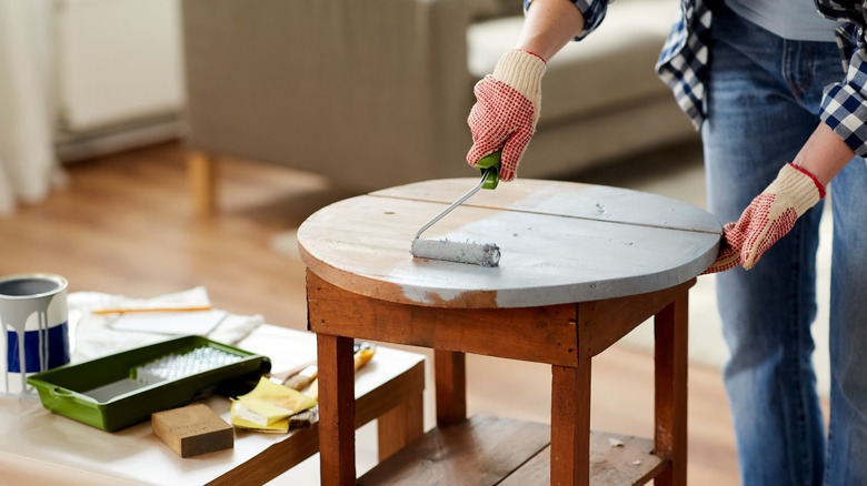 woman painting table with roller