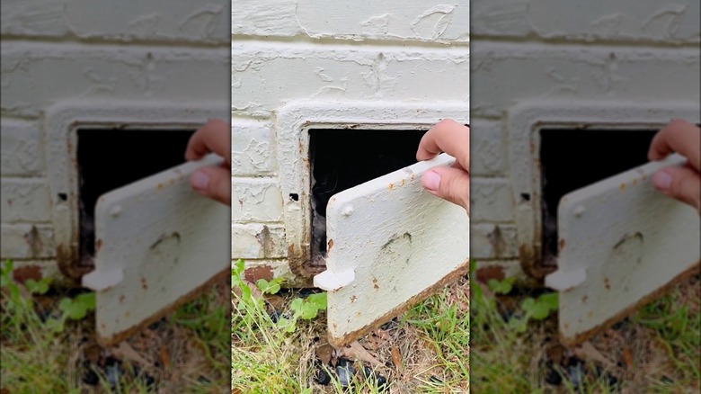 person opening a clean-out door