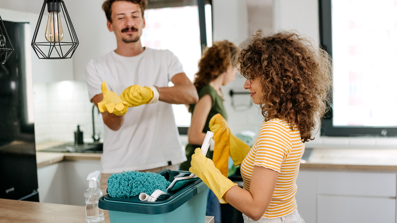 Friends prepare to clean together in a kitchen