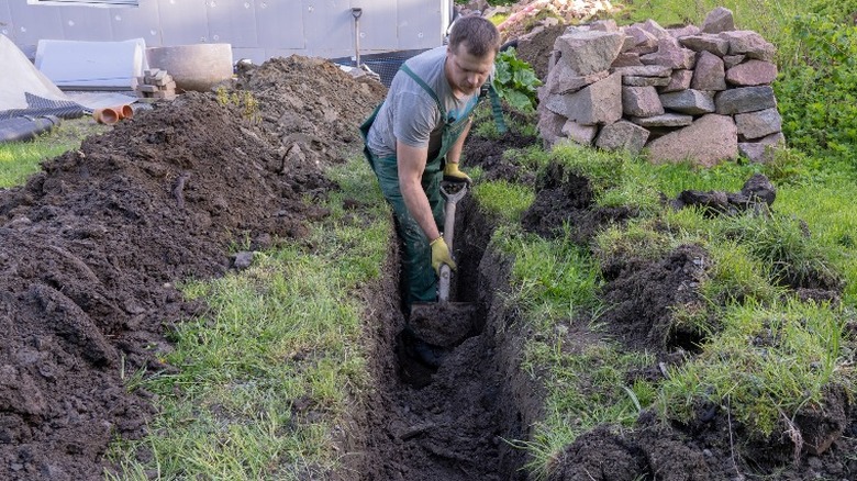 man digging trench with shovel