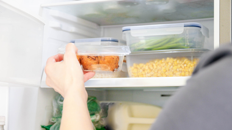 Person putting food containers in a fridge.