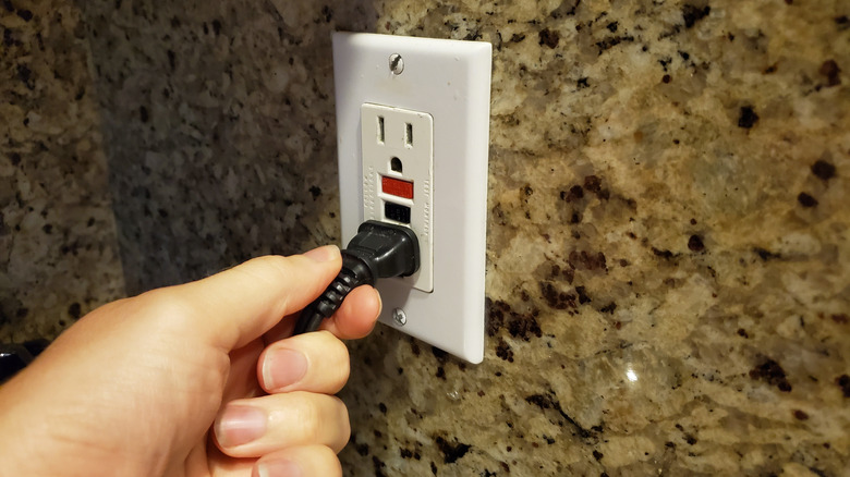 Person plugging a cord into a GFCI receptacle