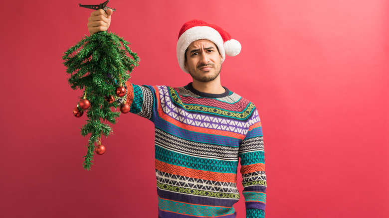 man holding upside down christmas tree