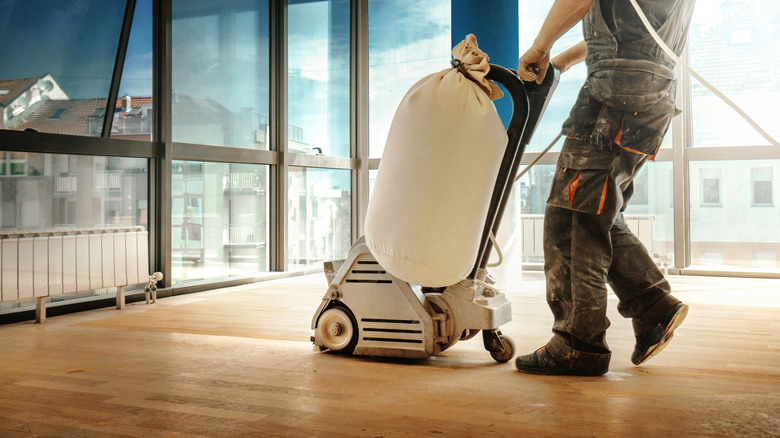 Man using a sanding machine on wood flooring