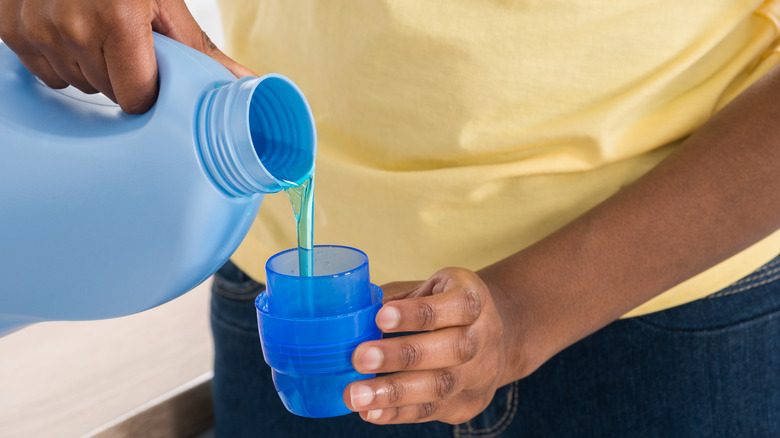 person pouring detergent into cup