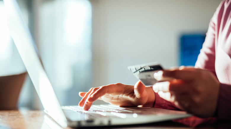 Person holding credit card using computer