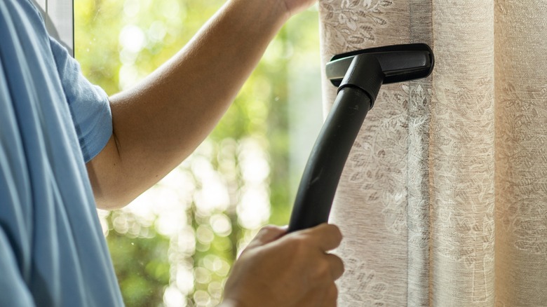 Woman vacuuming drapes