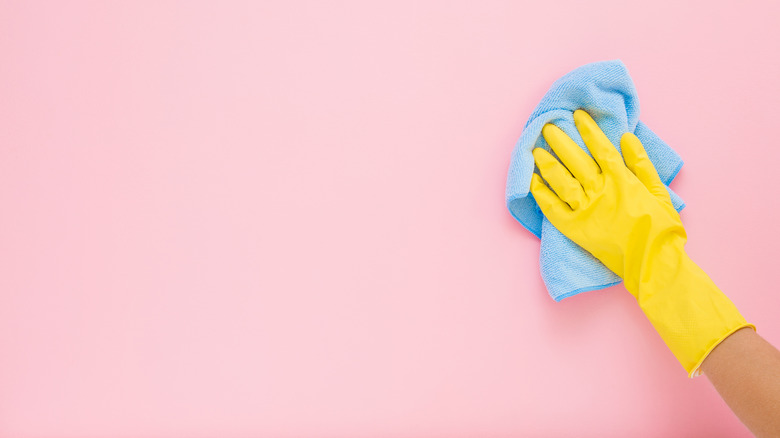 Person's gloved hand wiping wall