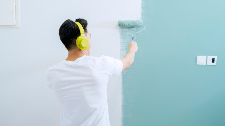 Young man painting wall blue