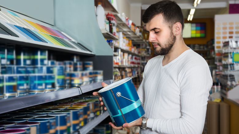 Man choosing paint at hardware store