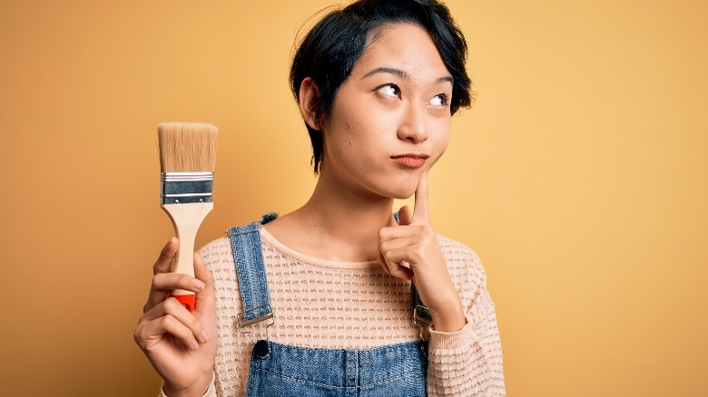 thoughtful woman holding paint brush