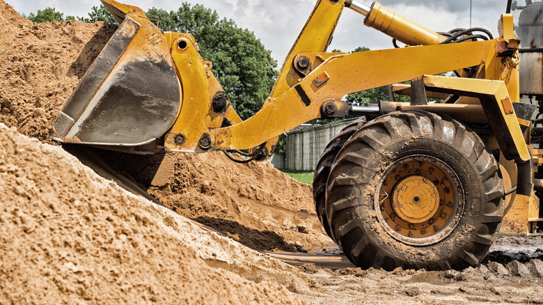 Bulldozer scoops dirt from mound