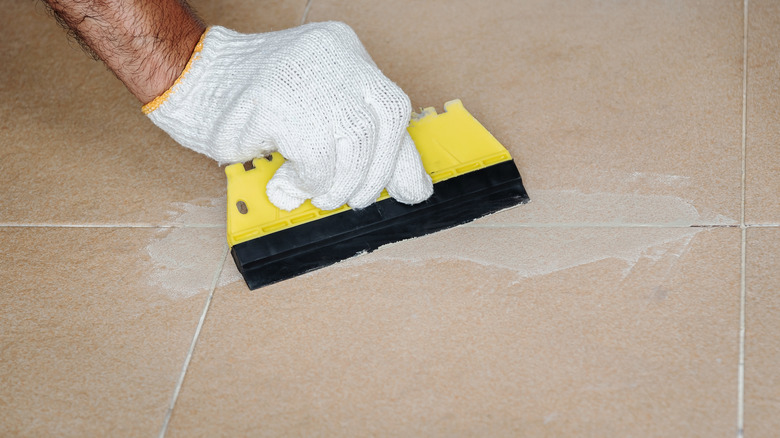 man applying grout with tool