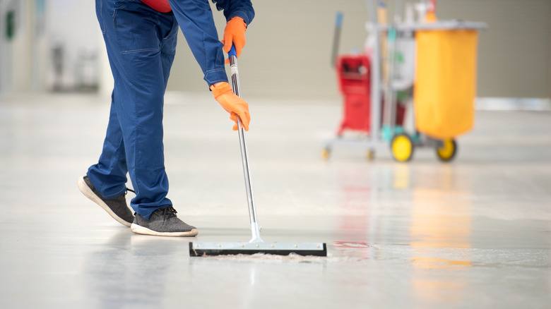 Custodian cleaning floor with mop