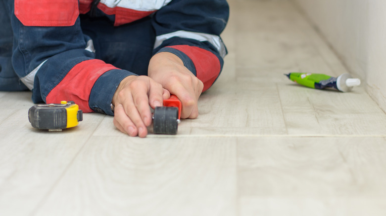 Worker using tools to install linoleum