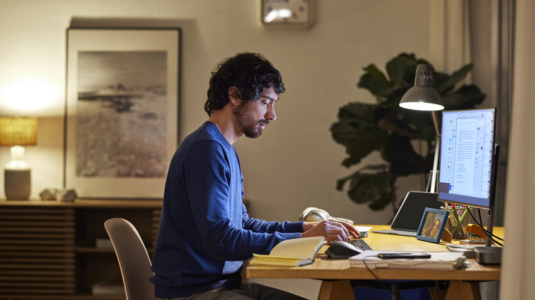 Man working at a computer in a lamplit home office