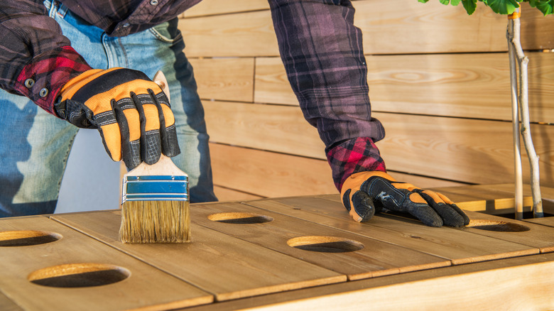 man with brush sealing wood