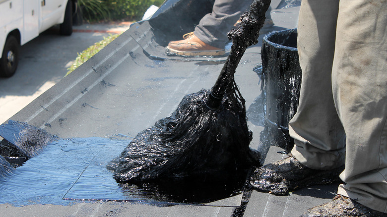 A worker laying down tar on a roof top