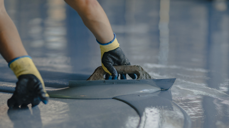 Spreading cement mixture onto floor