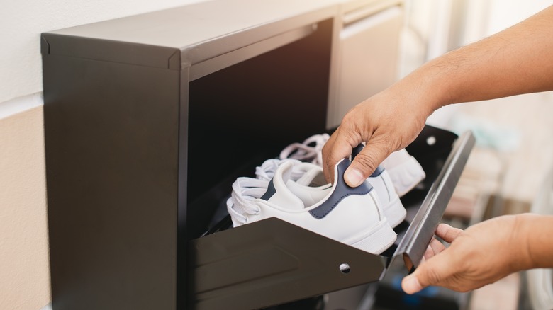 person placing sneakers in cabinet