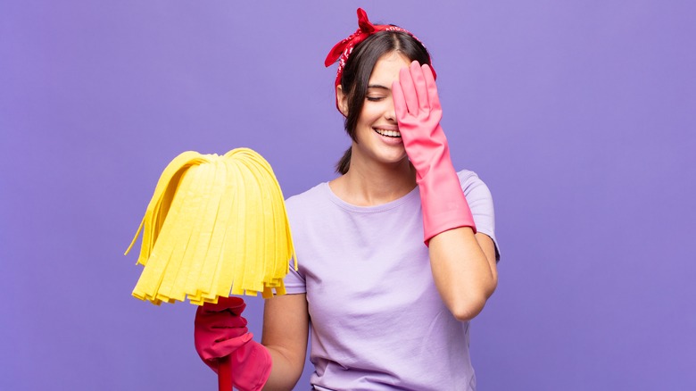 Woman holding mop touching face