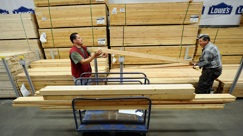 Two men loading lumber from Lowe's onto a cart