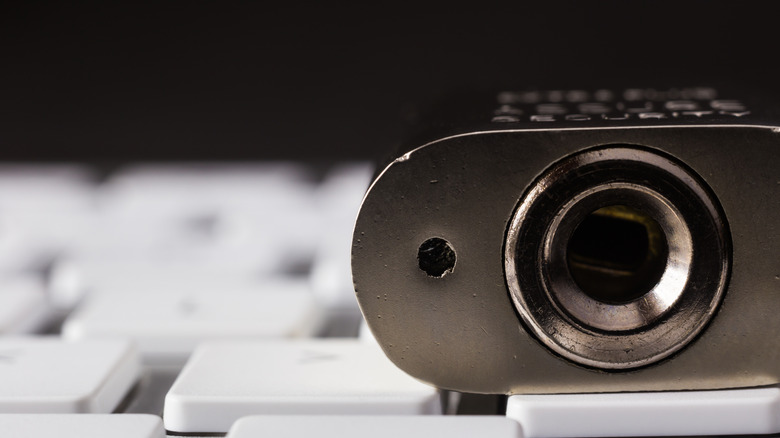 closeup of chrome padlock placed on a keyboard with the focus on the keyhole and tiny hole beside keyhole