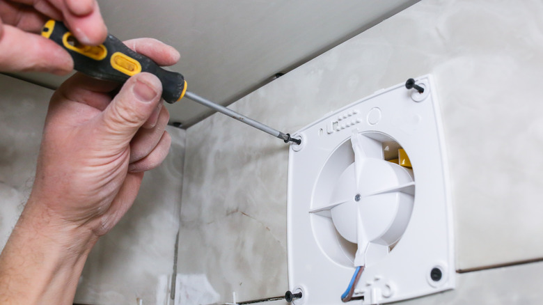 person fixing bathroom exhaust fan