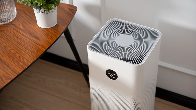 Angle of white air purifier on floor next to wooden table