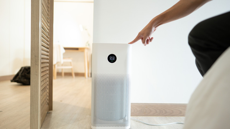 Hand presses a button on the air purifier