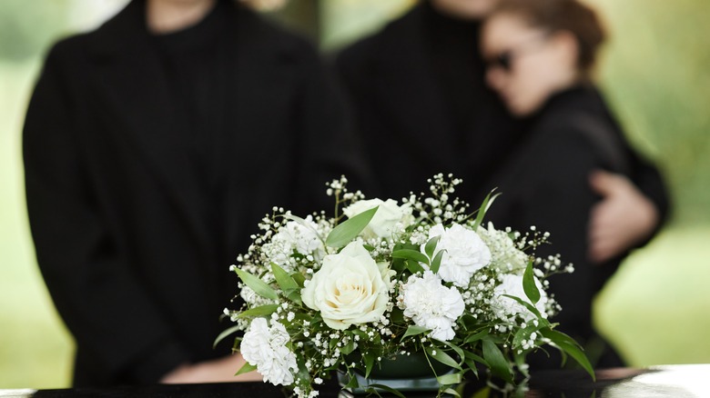 Funeral flowers and people in background