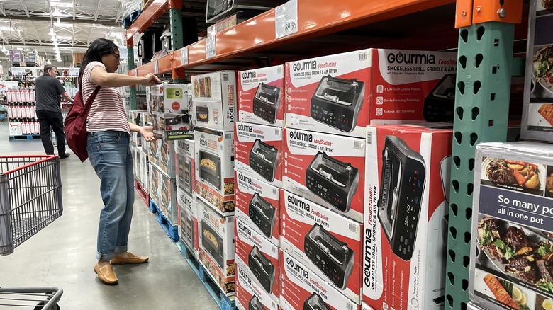 A woman looks at a box of cookware in the aisle at Costco