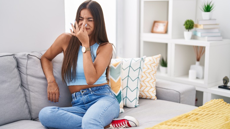 Woman on sofa holding nose