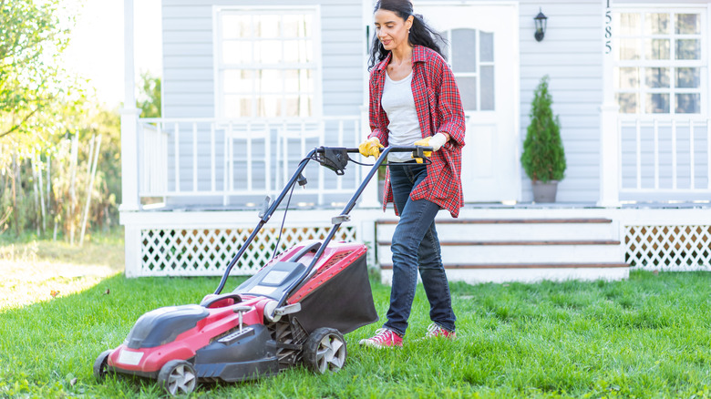 woman mowing grass lawn outside