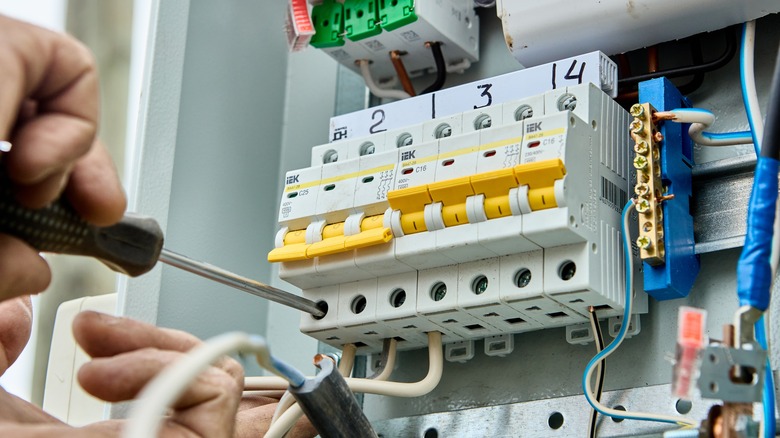 A person repairs a fuse box fault