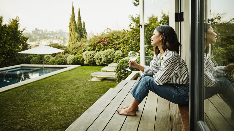 woman sitting on deck and looking at her backyard