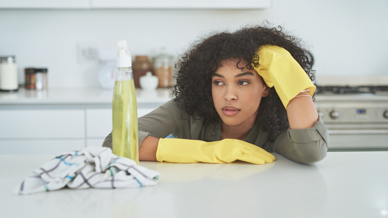 tired woman looking at cleaning spray