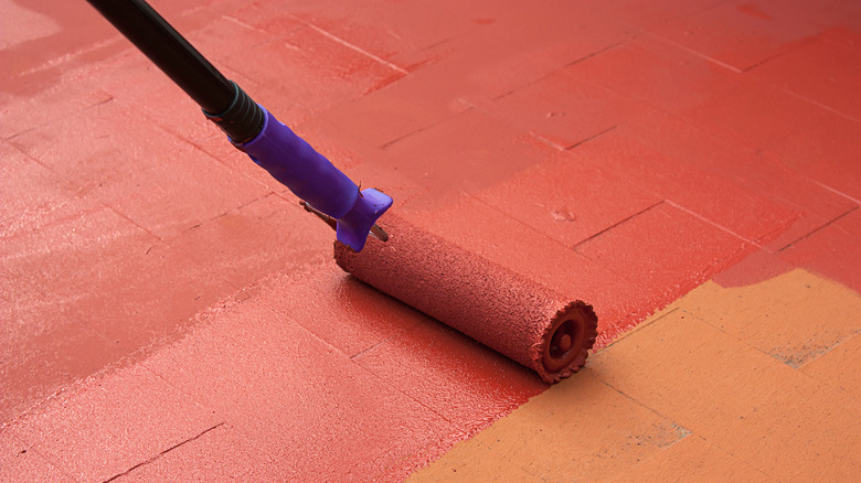 person rolling paint on a deck