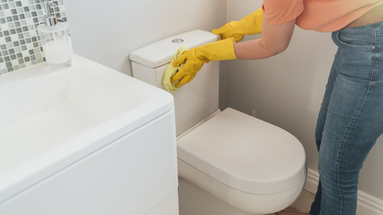 Woman putting lid on toilet tank