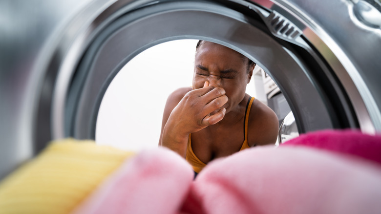 Woman smelling odor in washing machine