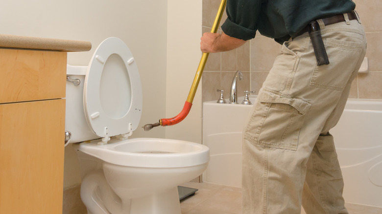 Using toilet auger to unclog toilet