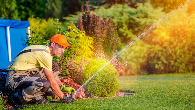 worker adjusting sprinkler head