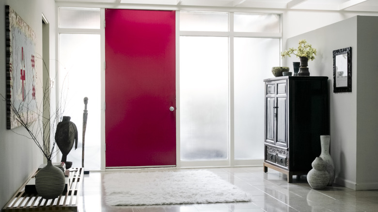 Spacious entryway with square plush rug, bench and armoire on either side