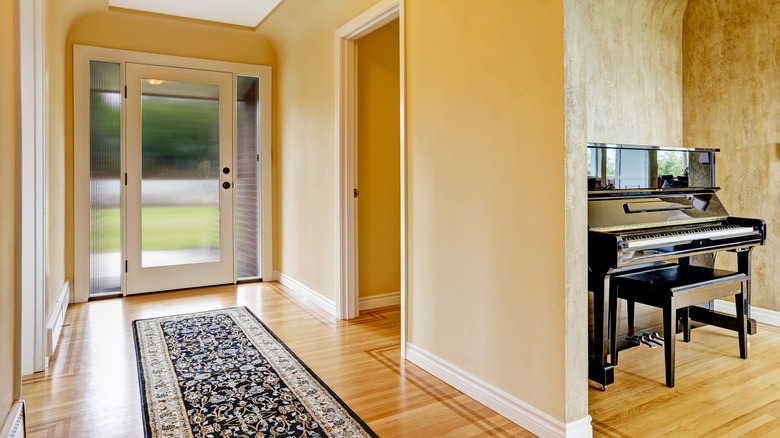 Entrway hallway with runner, piano in next room