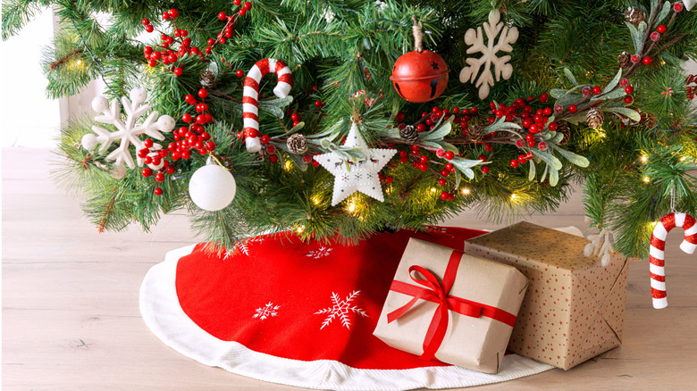 The bottom of a decorated Christmas tree is hidden by a red skirt