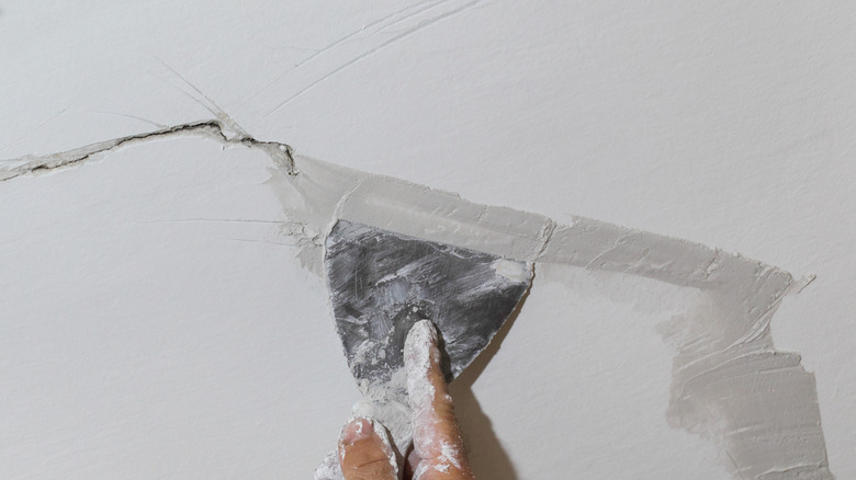 Person filling ceiling crack with spackle